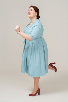 片足でバランスをとる青いドレスを着た女性の側面図