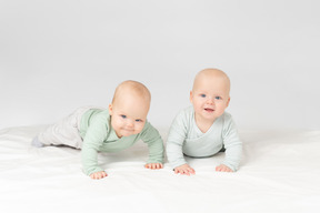 好奇心が強い赤ちゃん双子の胃の上に横たわる