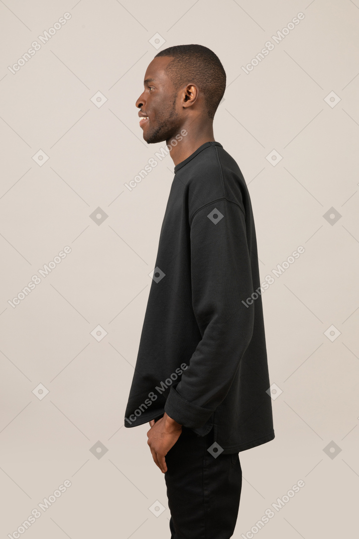 Улыбающийся молодой человек стоит с руками в карманах