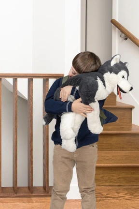A little boy hugging a husky stuffed animal