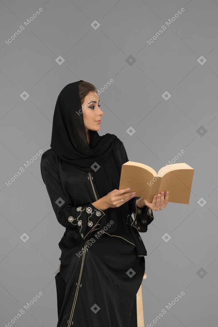 穆斯林妇女拿着本书侧身看