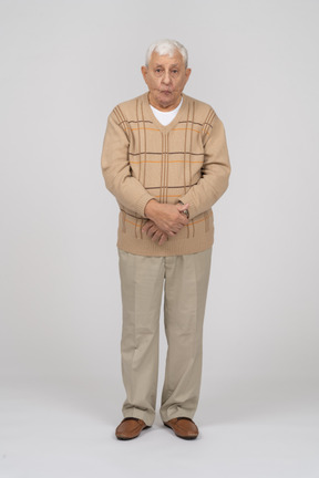 Front view of an old man in casual clothes making faces