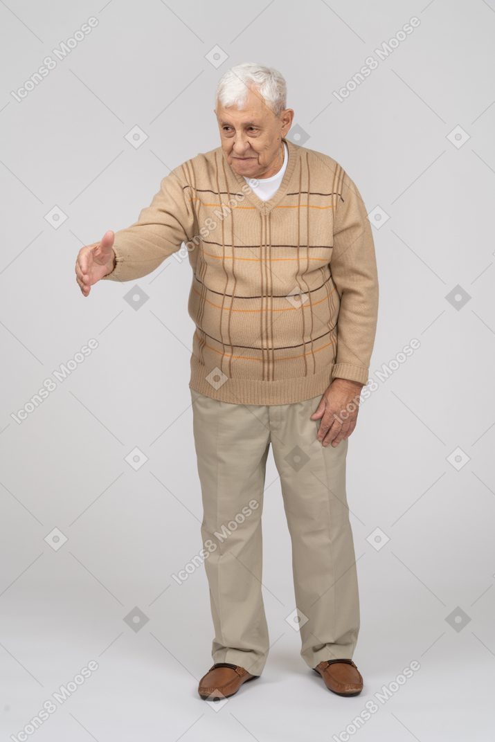 Vista frontale di un vecchio felice in abiti casual che dà una mano per scuotere