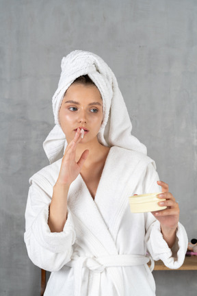 Mujer en bata de baño aplicando crema facial
