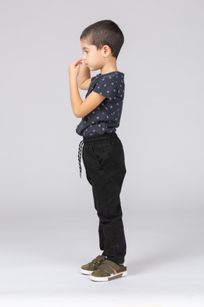 Side view of a boy in casual clothes touching nose