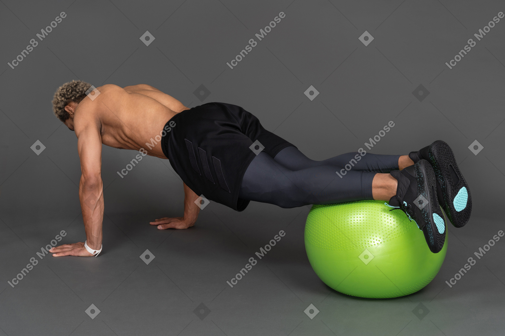 Vista traseira de três quartos de um homem afro sem camisa fazendo flexões em uma bola de ginástica
