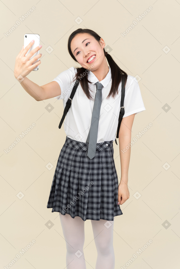Menina da escola asiática fazendo uma selfie