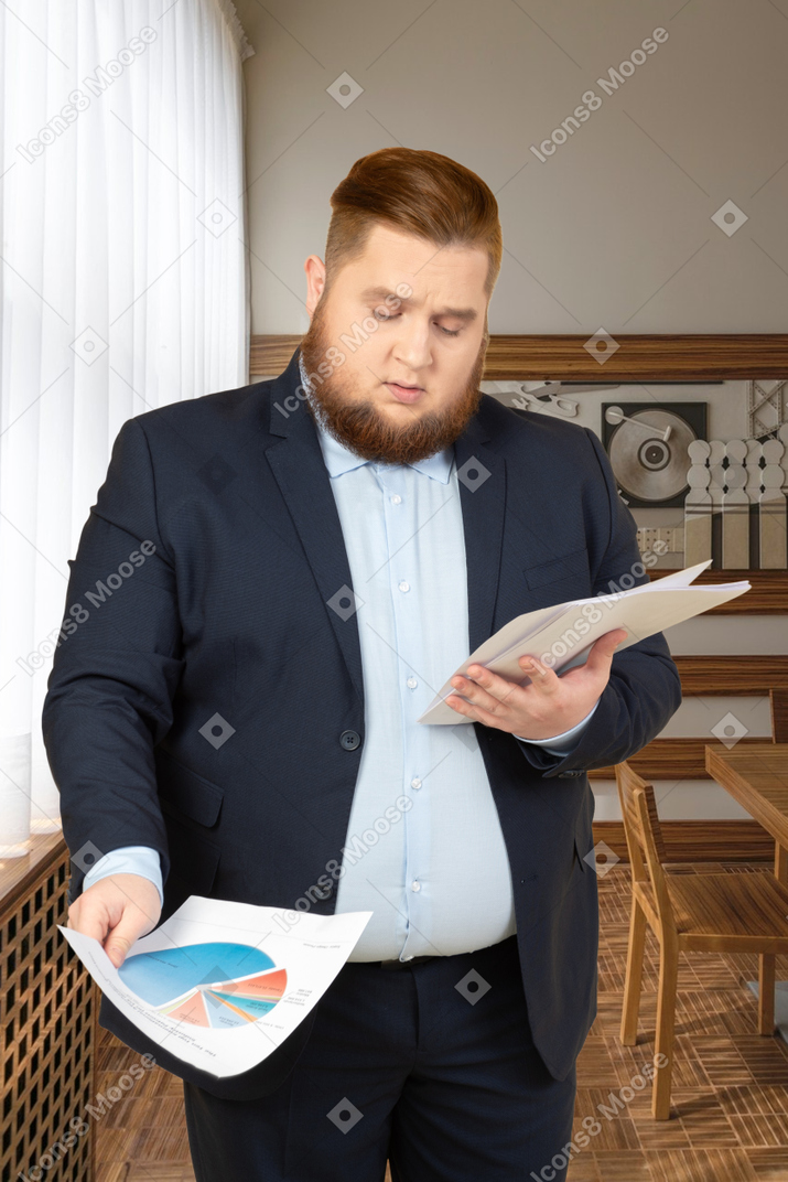 A man in a suit looking at papers in the office