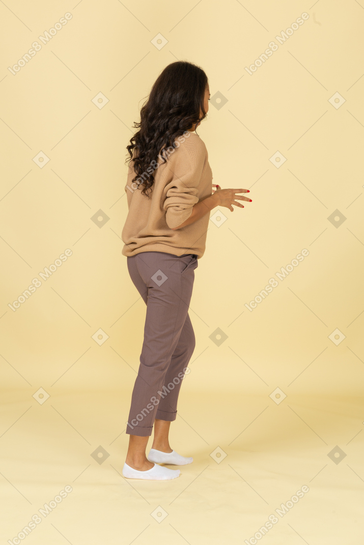 Вид сзади в три четверти темнокожей молодой женщины, разводящей пальцы