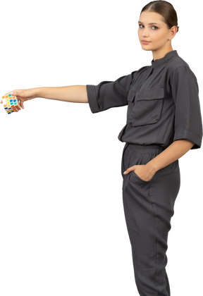 Three-quarter view of young woman in a jumpsuit holding a rubik's cube