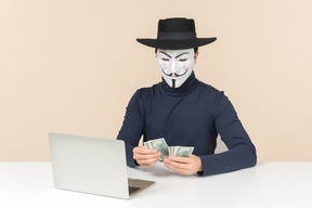 Hacker wearing vendetta mask counting money