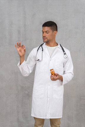 Молодой врач со стетоскопом смотрит на таблетку