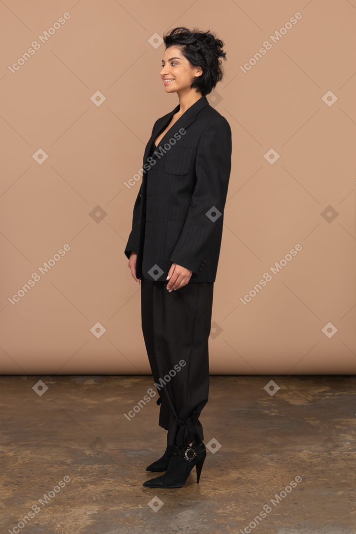 Трехчетвертный вид улыбающейся деловой женщины в черном костюме