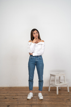 Mulher de blusa branca e jeans fica pensando