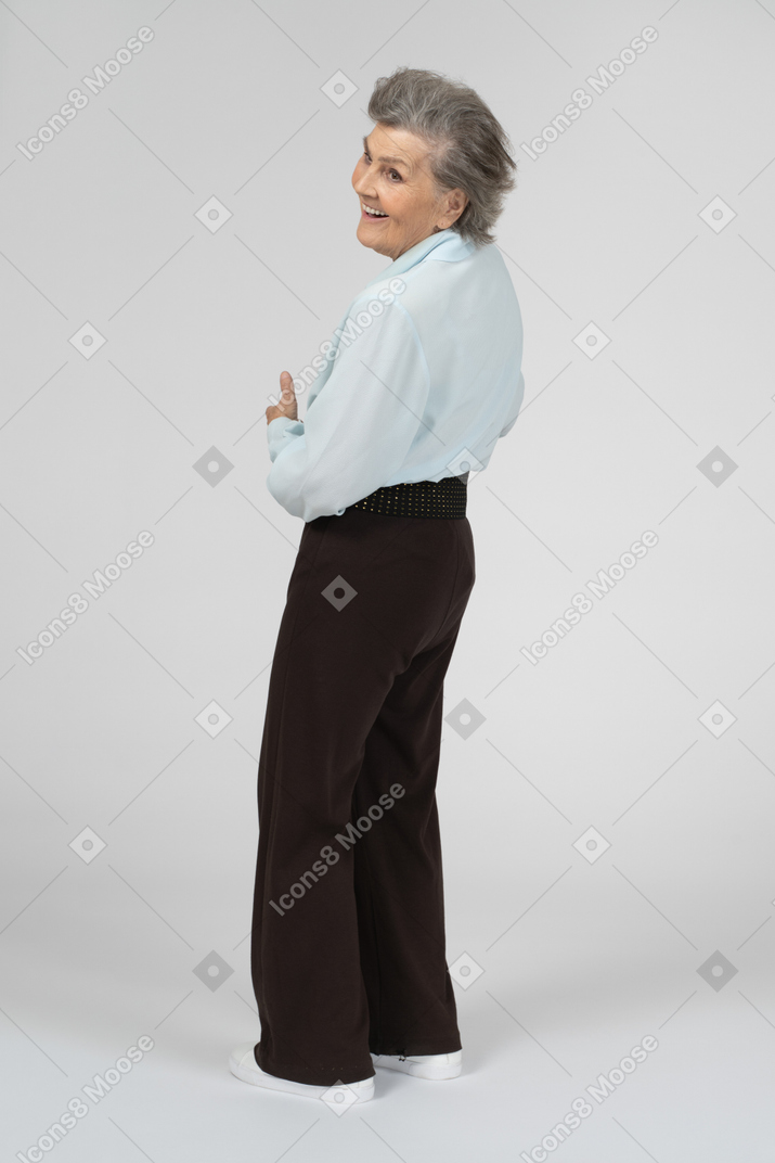 Vista posteriore di tre quarti di una donna anziana che sorride sopra la sua spalla
