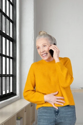 A woman in a yellow sweater talking on a cell phone