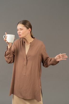 Young woman wincing while drinking coffee