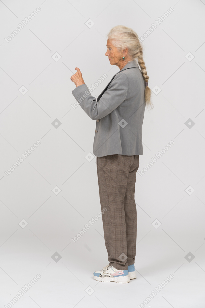 Vista laterale di una vecchia signora in abito che indica con un dito