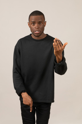 Man in black clothes looking at camera and pointing down