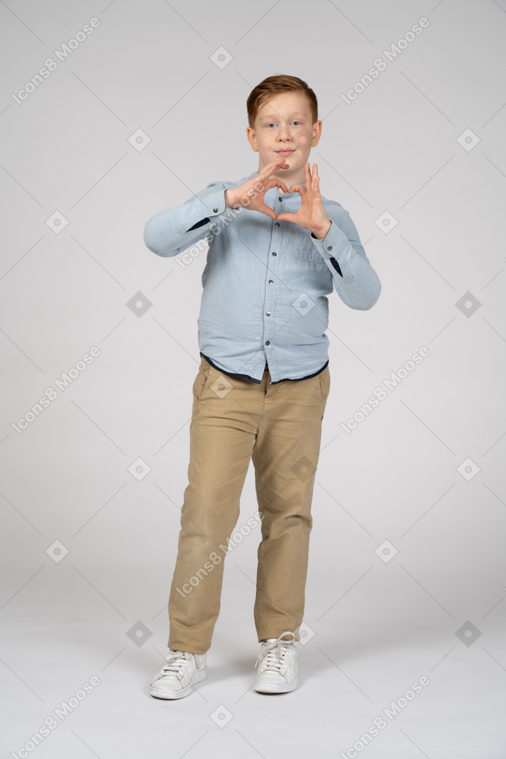 Front view of a boy making heart with fingers and looking at camera