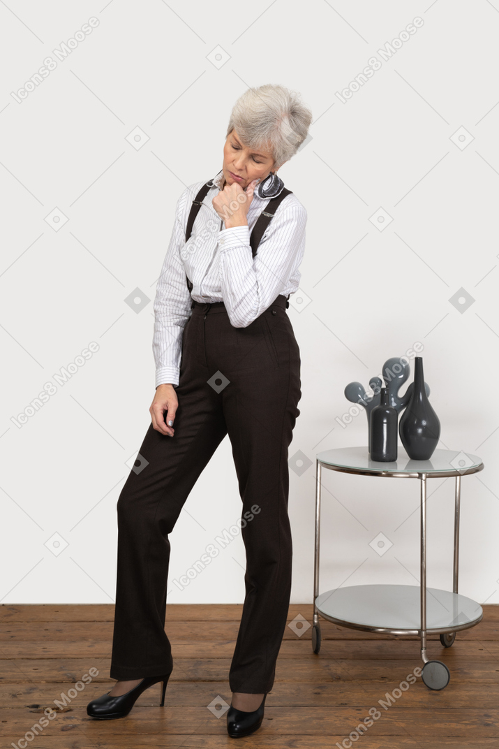 Three-quarter view of a sleepy old lady in office clothing touching her face
