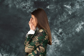 Side photo of young female in green japanese jacket hides her face