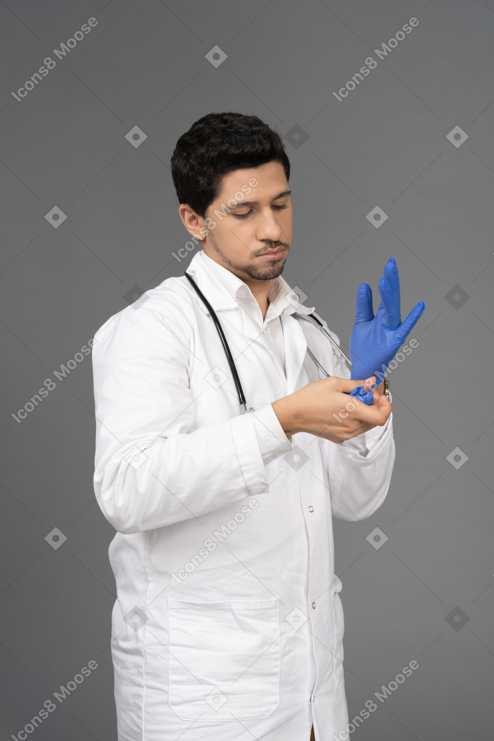 Доктор надевает синие перчатки