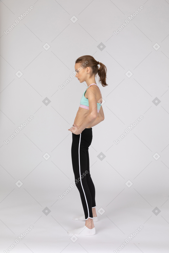 Side view of a teen girl in sportswear putting hands on hips