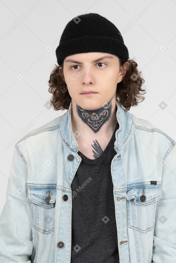 Retrato de um adolescente sério vestindo jaqueta jeans e chapéu de malha