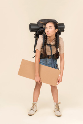 Tired looking young female hitchhiker holding paper card