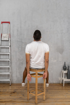 Back view of young man sitting on chair