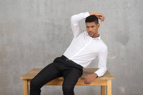 Homem em roupas de escritório, sentado em uma mesa e posando