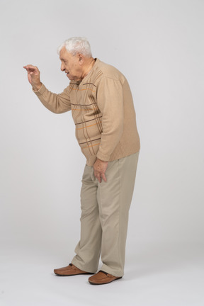 Vista lateral de um velho em roupas casuais, mostrando o tamanho de algo