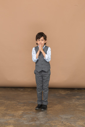 Vista frontale di un ragazzo in abito grigio che fa un gesto di preghiera