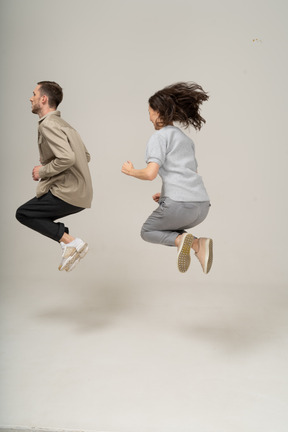 Side view of young man and woman in air with folded legs