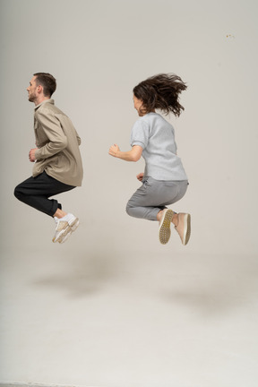 Vue latérale d'un jeune homme et d'une femme dans l'air avec les jambes repliées