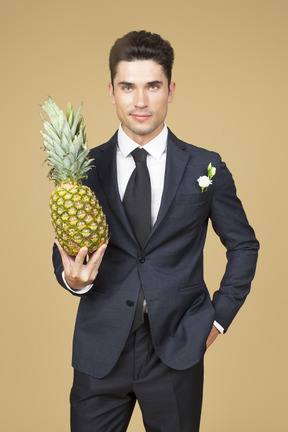 Groom in wedding suit holding a pineapple