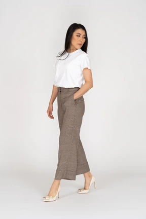 Three-quarter view of a walking young lady in breeches and t-shirt looking aside