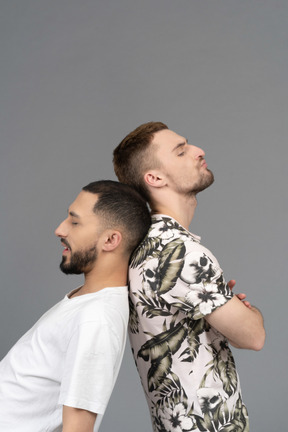 Close-up of two men standing unevenly back to back