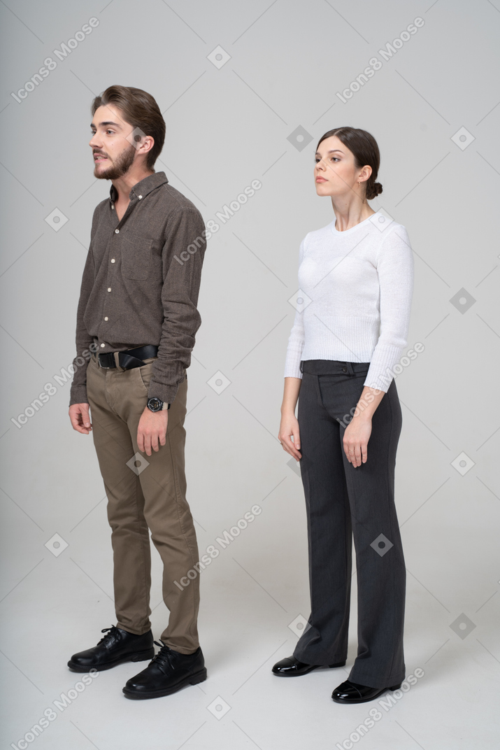 Vista de tres cuartos de una pareja joven en ropa de oficina levantando la cabeza