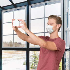 Mann mit gesichtsmaske, der ein selfie macht