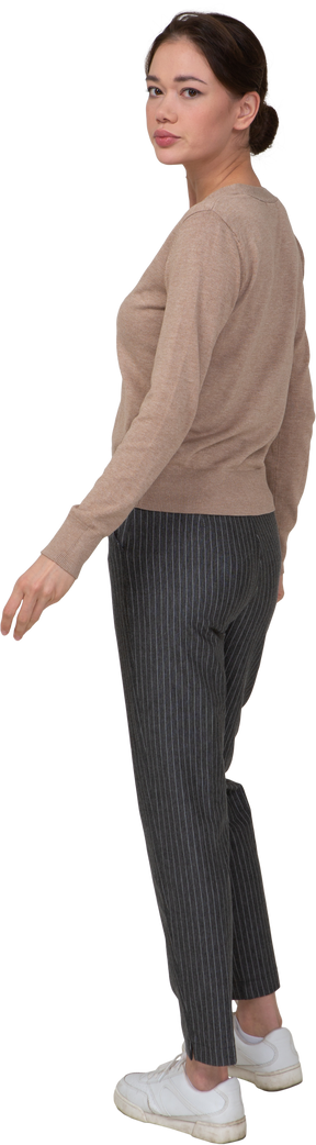 Vista posteriore di tre quarti di una giovane donna in pullover beige che si allontana