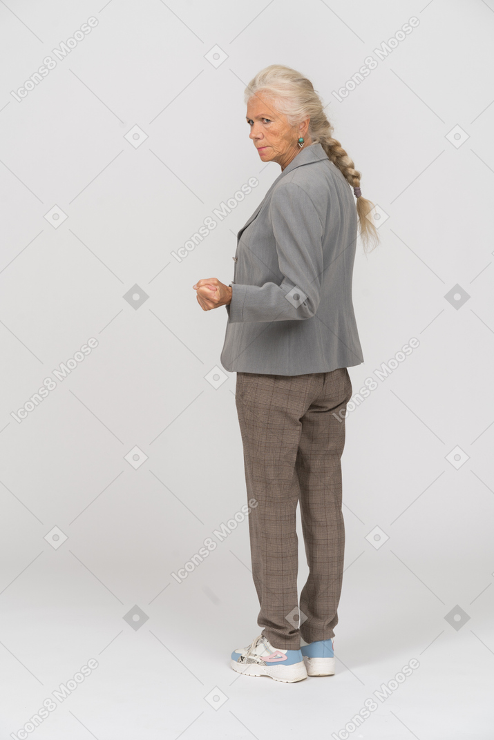 Rear view of an old lady in suit showing fist