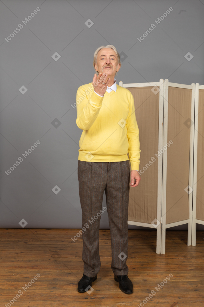 Front view of a questioning old man raising his hand