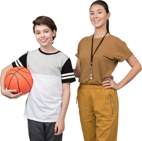 Учитель физкультуры стоит рядом с учеником, который держит баскетбольный мяч