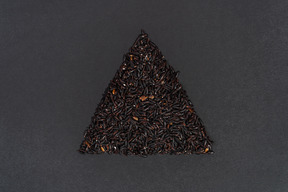 Black rice shaped in a triangle on black background