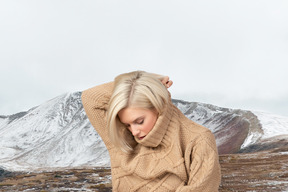 A woman with blond hair wearing a tan sweater