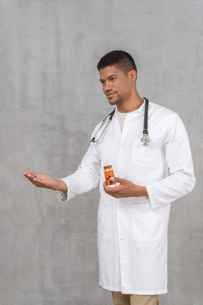 Young male doctor offering a pill