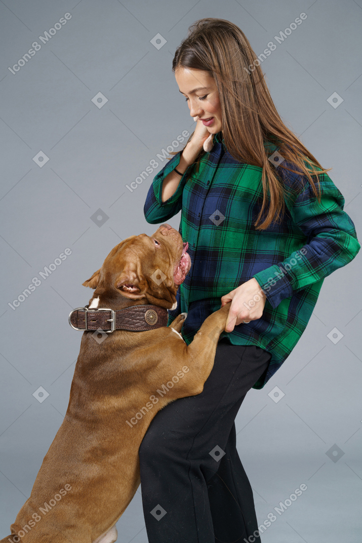 Close-up de um bulldog marrom brincando com uma dona sorridente, olhando para o lado e sorrindo