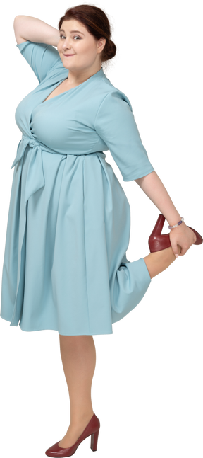 Vista frontale di una donna in abito blu in equilibrio su una gamba